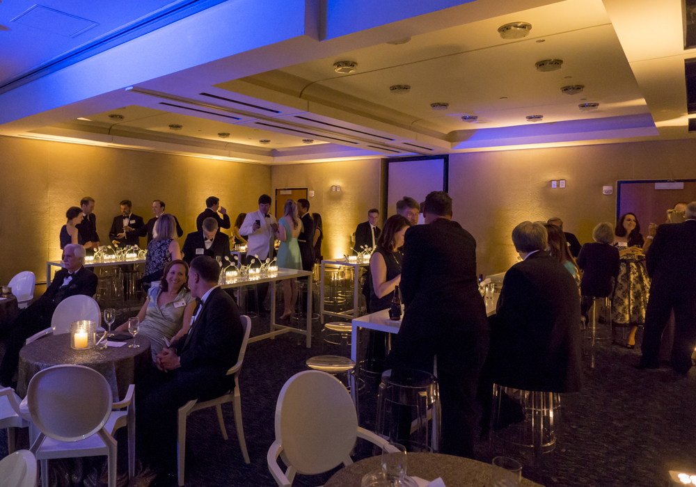 Group congregating in the dimly lit Founders Club around tables and chairs