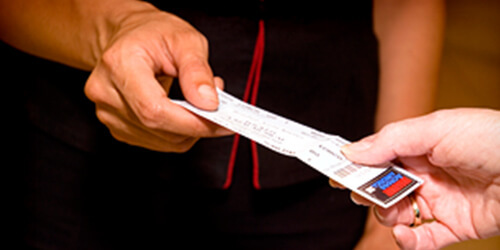 Two people's hands exchanging a ticket from one person to the other