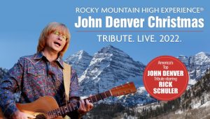 A picture of an actor dressed like John Denver Playing guitar 