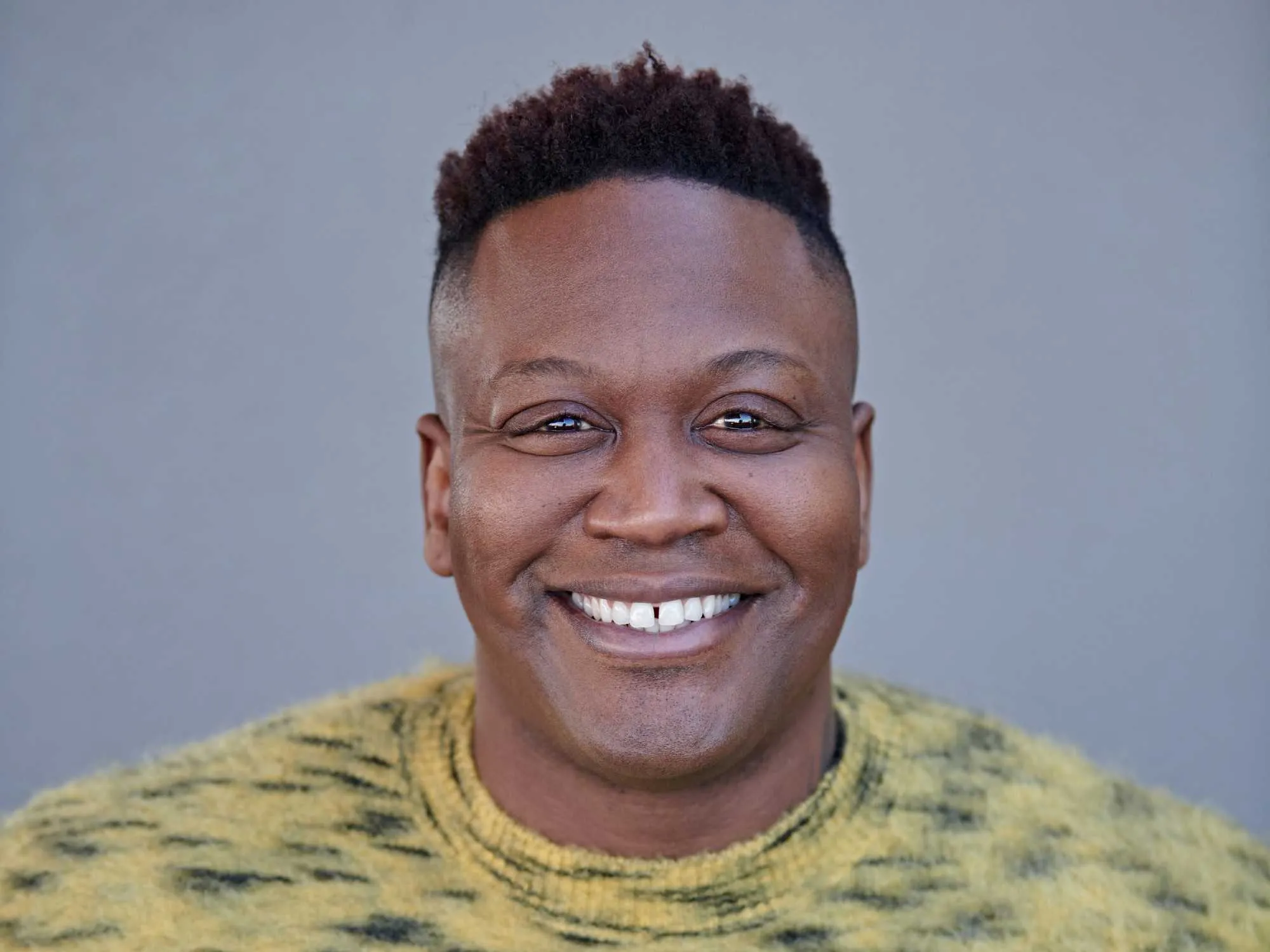 Tituss Burgess picture wearing a yellow shirt.
